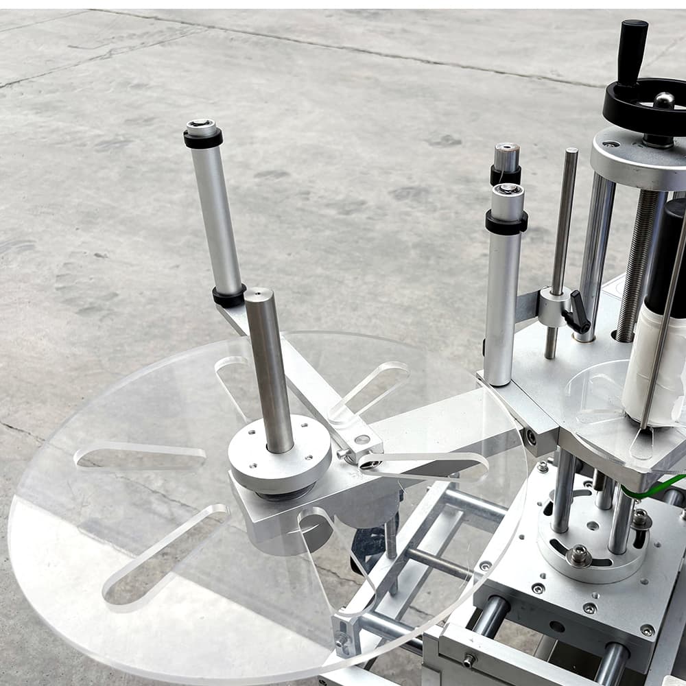FEYVAN round-bottle labeler showing the label reel, rollers and container guide on the machine. Reference equipment photograph.
