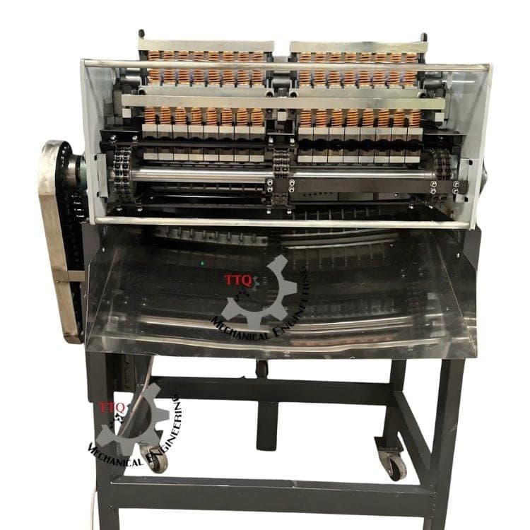 TTQ cashew shell-cutting machine with paired spring-loaded nut holders, cutting heads and a collection chute. Reference equipment photograph.