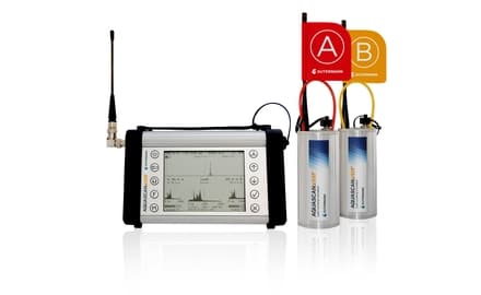 Leak correlator display beside two wireless transmitting sensor units with red and yellow A/B flags. Reference equipment photograph.