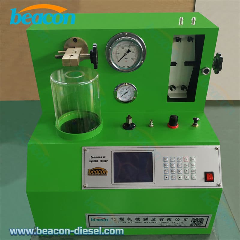 Green injector test unit with a pressure gauge, flow-measuring tube and protected spray viewing chamber. Reference equipment photograph.