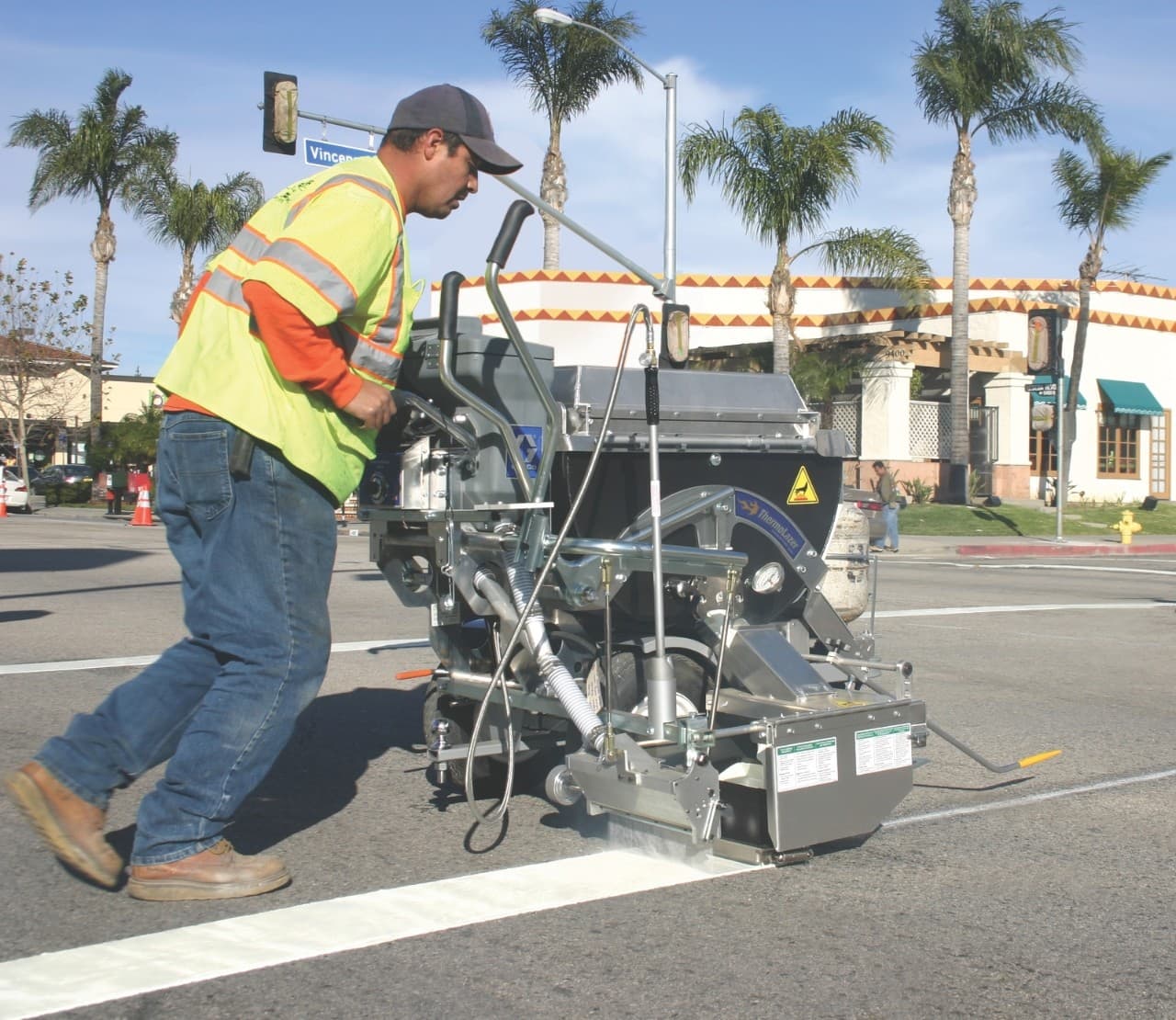Graco walk-behind thermoplastic marking machine being operated on a paved work area. Reference equipment photograph.