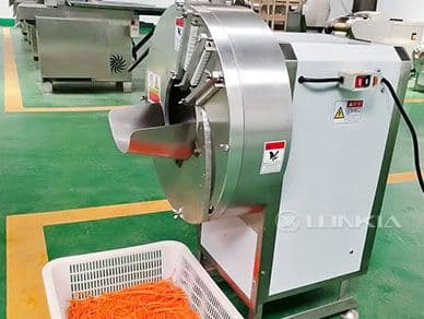 LONKIA ginger slicing machine photographed in a factory with its circular cutting enclosure and feed guide. Reference equipment photograph.