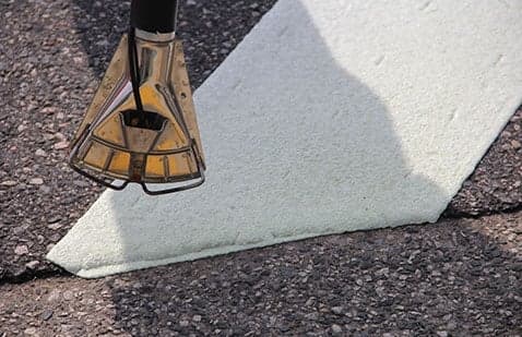 Ennis-Flint propane heat-torch nozzle working above a preformed pavement marking. Reference equipment photograph.