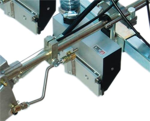 Reflective glass bead dispenser with its mounting bracket, feed hose and line-side distribution unit. Reference equipment photograph.