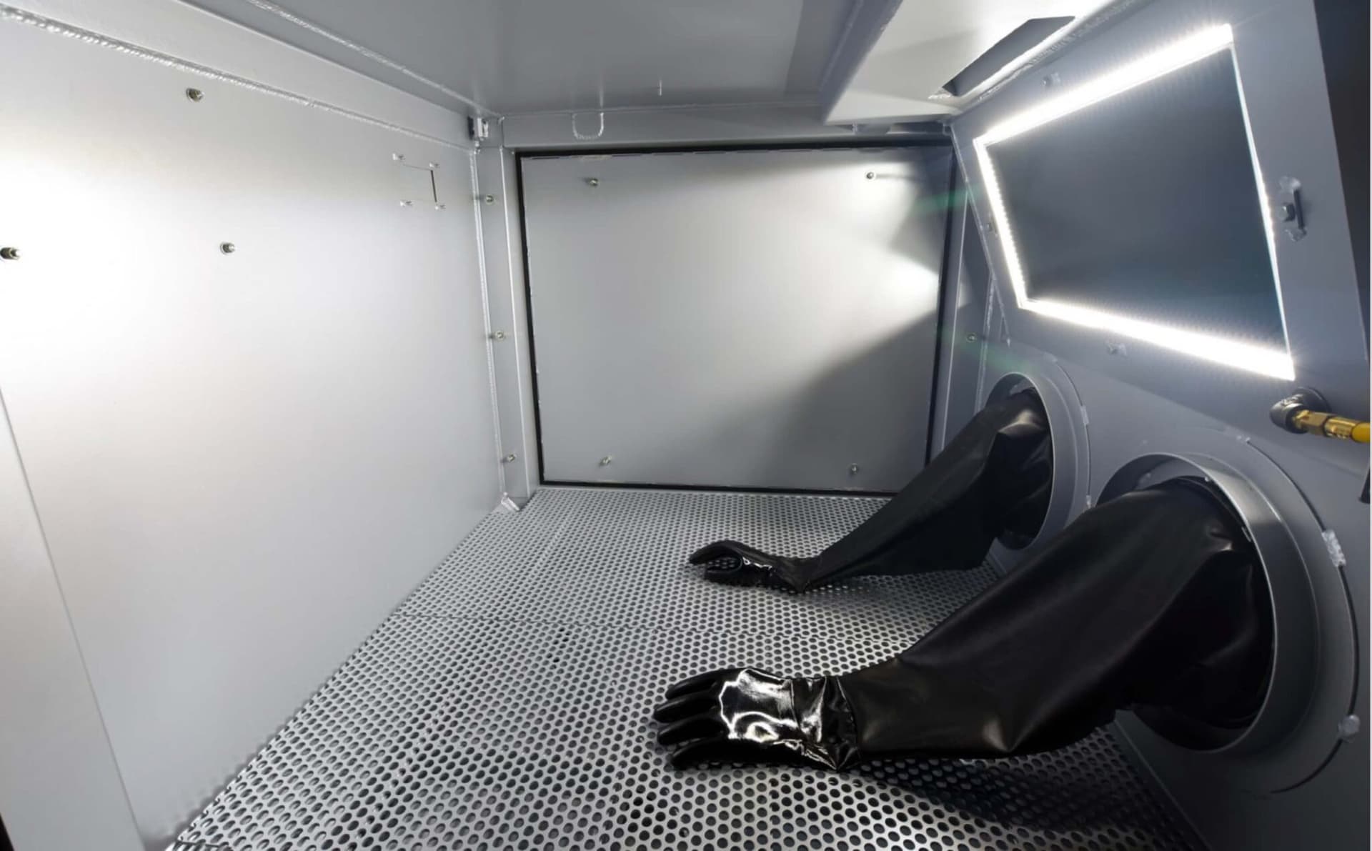 Interior of a Titan abrasive blast cabinet with gloves and illuminated work area. Reference equipment photograph.