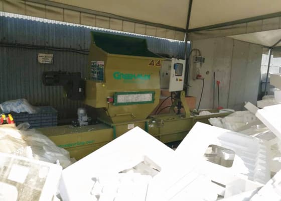 GREENMAX A-C100 foam compactor photographed in an operating recycling area with EPS foam feedstock. Reference equipment photograph.