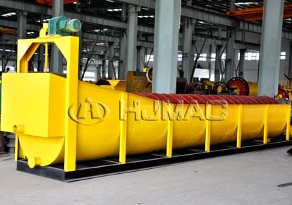 Long yellow spiral classifier tank with a red spiral and drive, photographed in a factory. Reference equipment photograph.