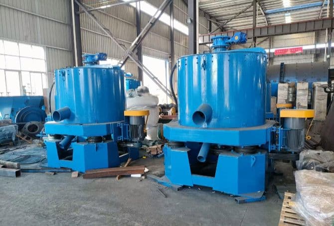 Blue centrifugal concentrators photographed on a factory floor, with drive and discharge connections. Reference equipment photograph.