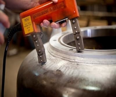 Raynox magnetic particle inspection yoke applied to a ferromagnetic workpiece. Reference equipment photograph.